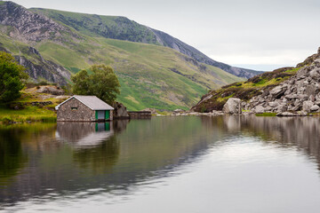 Obraz premium Ogwen cottage reflected into Llyn Ogwen on a grey, rainy, summer's day