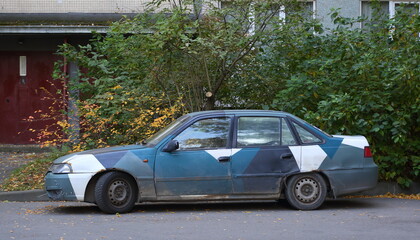 An old multicolored car at the entrance to a residential building, Iskrovsky Prospekt, St. Petersburg, Russia, October 2021