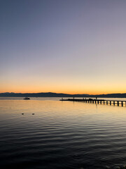 Obraz premium Idyllic orange sunset at the lake, silhouette of the mountains background