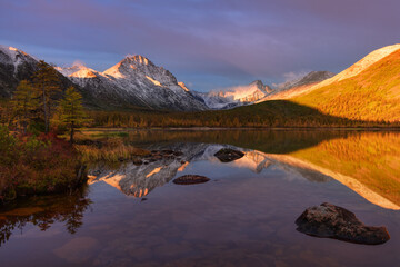 Mountain peaks in the snow illuminated by the red rays of the dawn sun