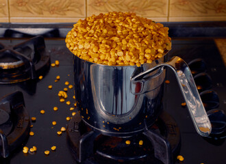 Boiled peas in a stainless saucepan with grains scattered over the gas stove