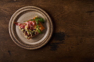 Piece of traditional Italian Roman pizza lies on rustic ceramic plate on brown wooden background, flat lay, copy space