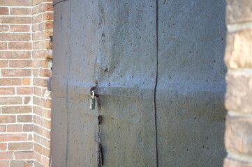 An old iron door on the lock of a brick building
