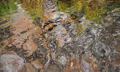 The abstract background is gray with orange-green spots of water ripples.