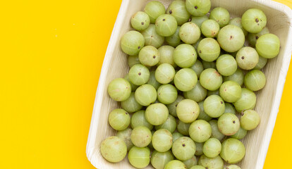 Fresh emblica in plate on yellow background.