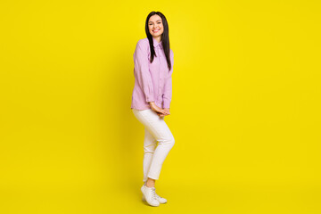 Full body profile photo of sweet brown hairdo young lady stand wear pink shirt trousers isolated on yellow color background