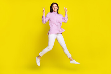 Fototapeta na wymiar Full length photo of hooray brown hairdo young lady run show v-sign wear pink shirt pants isolated on yellow color background