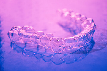 Invisible dental teeth brackets tooth aligners on pink background. Plastic braces dentistry...