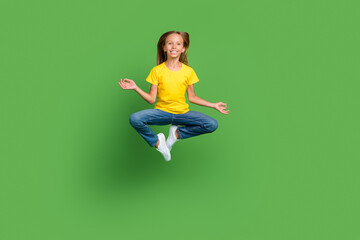 Full length body size view of attractive cheerful girl jumping meditating isolated over bright green color background