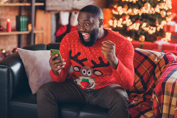 Photo of young excited black man happy positive smile rejoice celebrate victory smartphone noel...