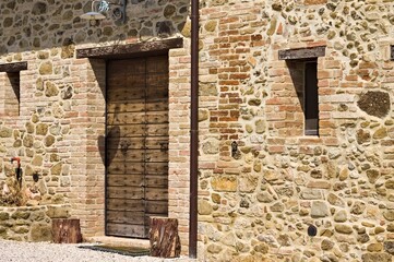 A facade of an old stone farmhouse with a wooden door and two little windows in the italian countryside (Tuscany, Italy, Europe) - 461451091