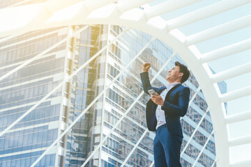 Young businessman in feeling happy because receive replies mail from business partners who agree to...