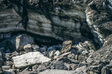 Nature background with icefall near glacier wall with cracks and scratches. Natural backdrop with icy wall and blocks of ice. Beautiful landscape with shiny glacial wall and ice blocks in sunlight.