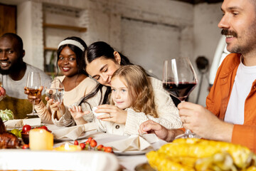 Happy family celebrate Thanksgiving day, sitting at table with roasted turkey and holiday traditional food, dishes. Drinking wine