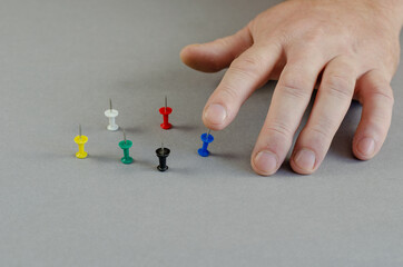 One Hand and push pins on gray background. Man presses one sharp