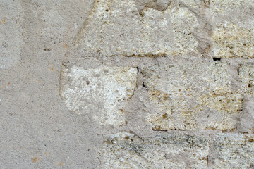 An old stone wall. Weathered wall with collapsed plaster. Shell