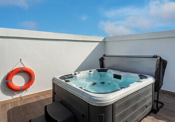 Luxury bathtub, jacuzzi for therapeutic massage and relaxation outside. Under the blue sky.