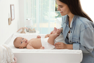 Mother changing her baby's diaper on table at home