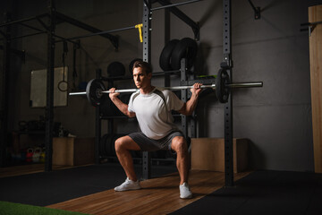 Fototapeta na wymiar full length view of athletic man exercising with barbell in sports center.