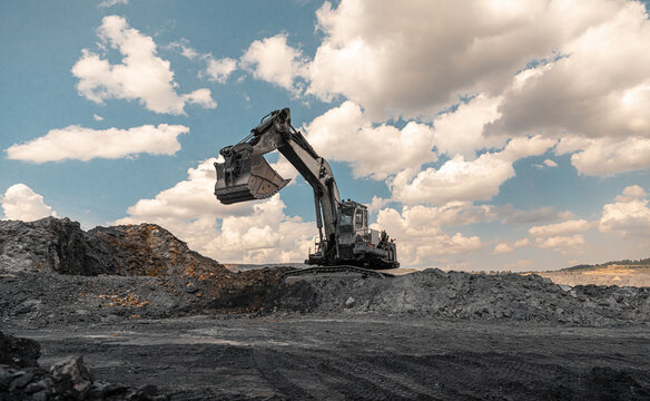 Large quarry dump truck. Big yellow mining truck at work site. Loading coal into body truck. Production useful minerals. Mining truck mining machinery to transport coal from open-pit production