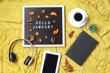 Hello January written on the letter board with multimedia accessories and coffee flat lay concept