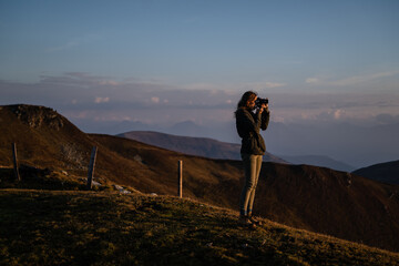 Junge Frau fotografiert nach Wanderung bei Sonnenaufgang am Berg in Salzburg Österreich