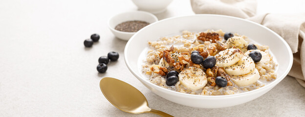 Oatmeal bowl. Oat porridge with banana, blueberry, walnut, chia seeds and almond milk for healthy...
