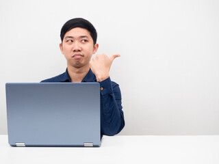 Man not satisfied sitting with laptop on the table point finger at copy space