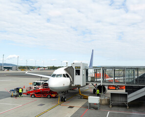 Boarding passengers on the plane through the boarding bridge. The plane lands at the international airport. Loading luggage. White airplane. Terminal Runway