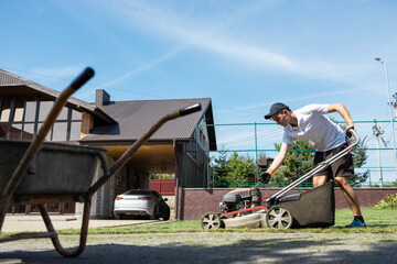 Male gardener starts a lawn mower