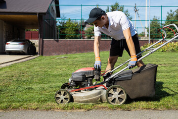 Male gardener unscrews the plastic fuel tank cap for a gasoline refueling lawn mower