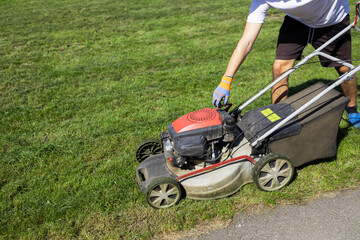 Man starts the engine of gasoline lawn mower
