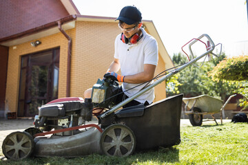 Man with a canister of gasoline in his hands refueling a lawn mower