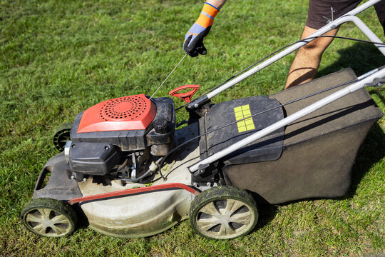 Man Starts The Engine Of Gasoline Lawn Mower