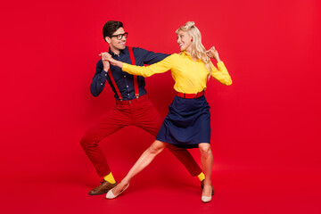 Full length body size view of attractive cheerful couple dancing twist festive day isolated over bright red color background