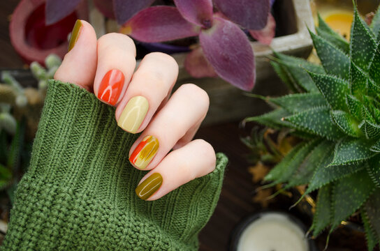 Closeup top view of beautiful faded colors trendy manicure of green and beige glossy nails. Winter or autumn style of nail design concept.