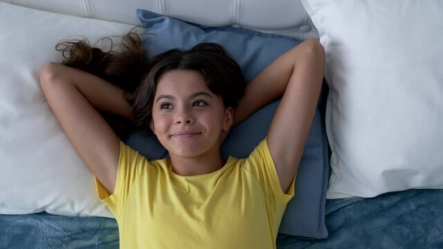 cheerful teen girl dreaming in bed, childhood