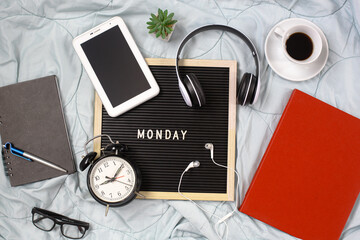 Monday flat lay concept with multimedia accessories, books and pens, glasses, alarm clock, flowers and coffee for refreshment on white background