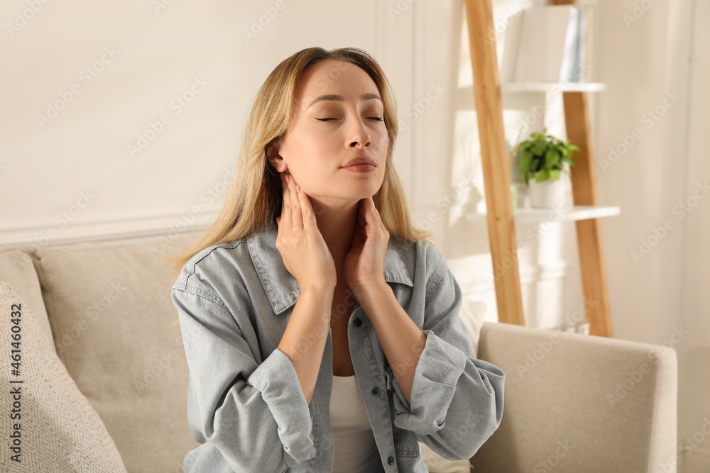 Wall mural Young woman doing thyroid self examination at home