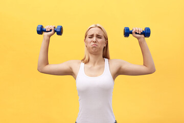 Fototapeta na wymiar Photo of serious young sports woman make exercises with dumbbells isolated over yellow wall background.