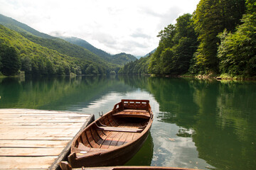 Old wooden boats are on the pier, on a beautiful mountain lake.
