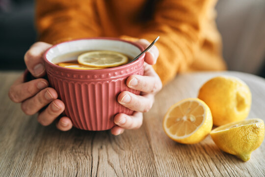 Hands holding a big cup of hot tea with lemon