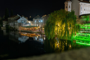 Fototapeta na wymiar Night shot of illuminated restaurants on a river bank in Trebinje