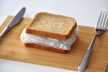 Sandwich with bread and plastic. Ready to eat with fork and knife. Huge threat for the food supply chain.