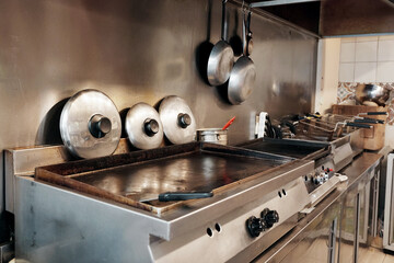 Industrial kitchen interior with grill, deep fryer and cooking pan