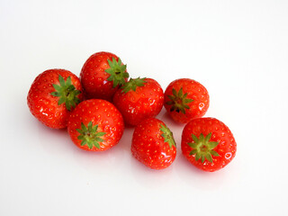 Perfect red strawberries on a white reflecting table in the daylight