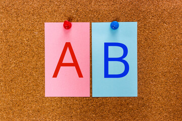 Conceptual 2 letters AB on multicolored stickers attached to a cork board. A user experience...