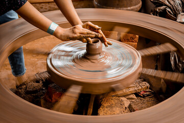A slow shutter speed shot of a potter hand making a pot from a pottery wheel at Hubli, Karnataka,...