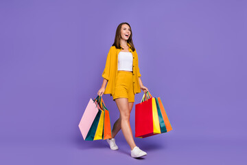 Full body photo of happy dreamy young woman walk shop mall sale season client isolated on purple...