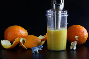 Grinding a fresh orange with a hand blender. Juicing. Concept picture for children with funny...